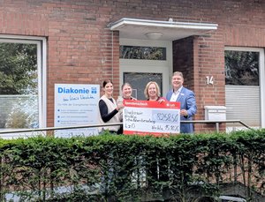 Andrea Tegenkamp und Angela Müller, Schuldnerberaterinnen, Martina Fisser, Geschäftsleitung des Diakonischen Werks Vechta, und Ingo Ruhe von der LzO stehen vor dem Gebäude des Diakonischen Werks und halten gemeinsam einen Spendenscheck über 8.258,50 Euro.